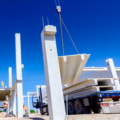 Crane loading concrete beam on flatbed trailer