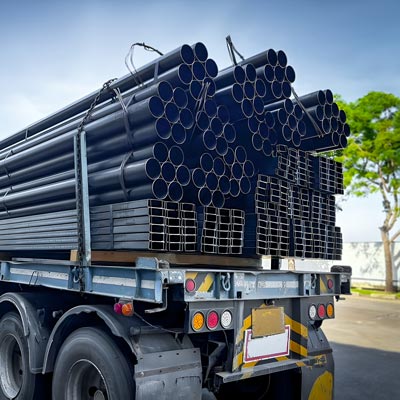Steel pipes stacked and secured on flatbed trailer